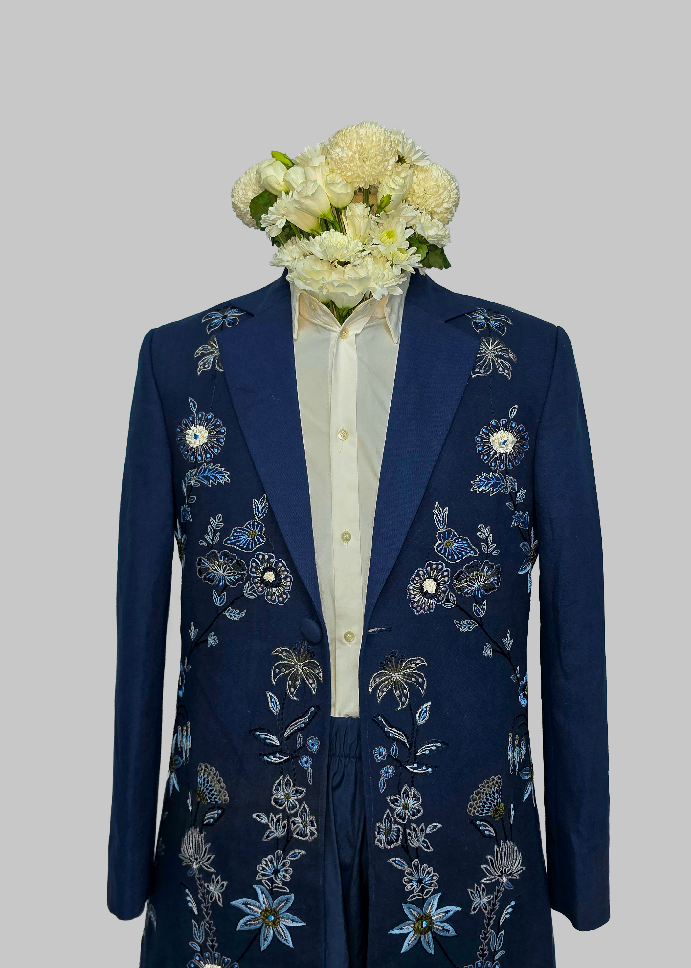 Navy blue embroidered long coat with floral patterns on a gray background