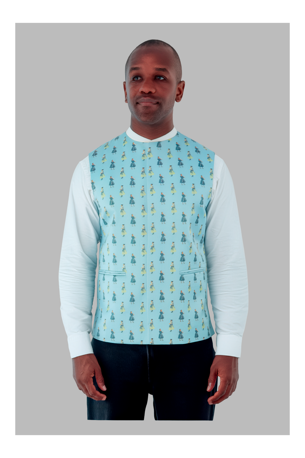 Man wearing a light blue patterned vest over a white long-sleeve shirt on a gray background