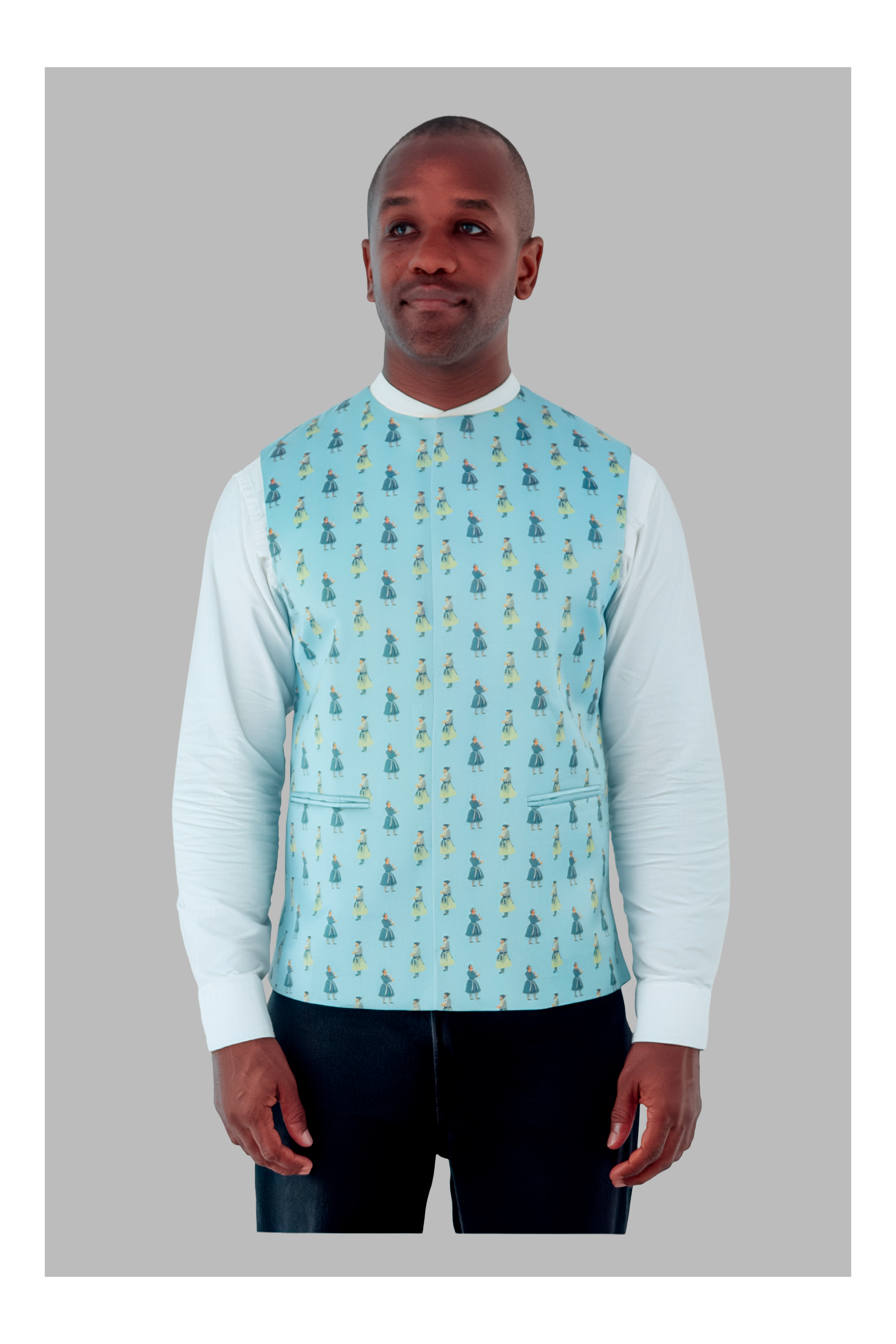 Man wearing a light blue patterned vest over a white long-sleeve shirt on a gray background