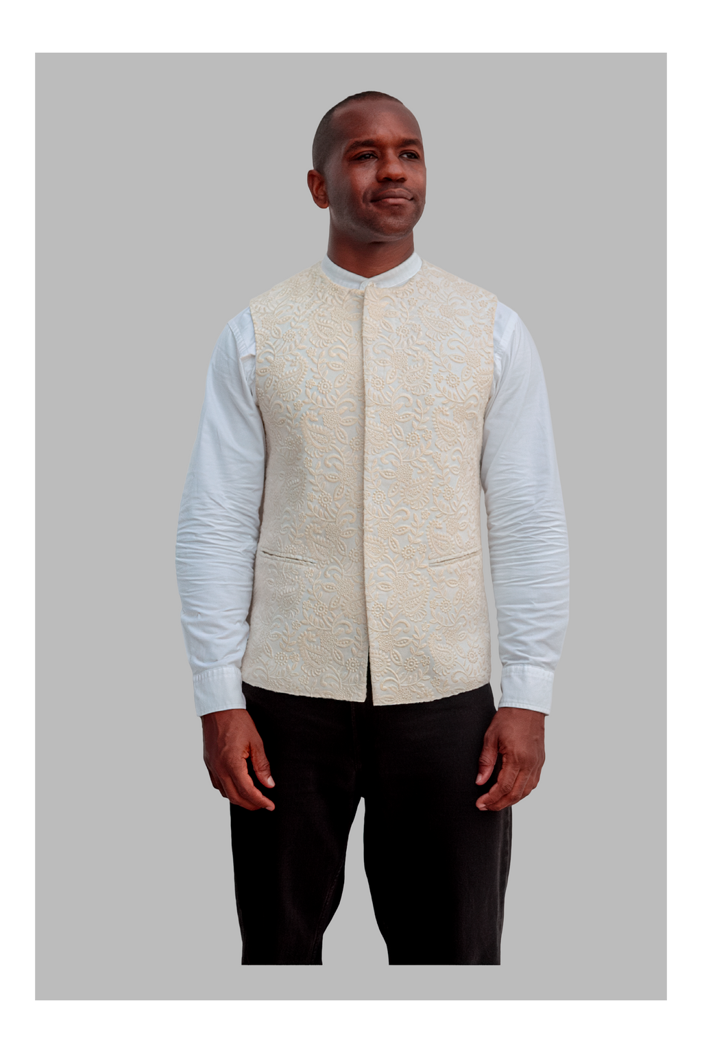 Man wearing a white patterned vest over a white shirt on a gray background