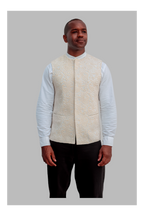 Man wearing a white patterned vest over a white shirt on a gray background