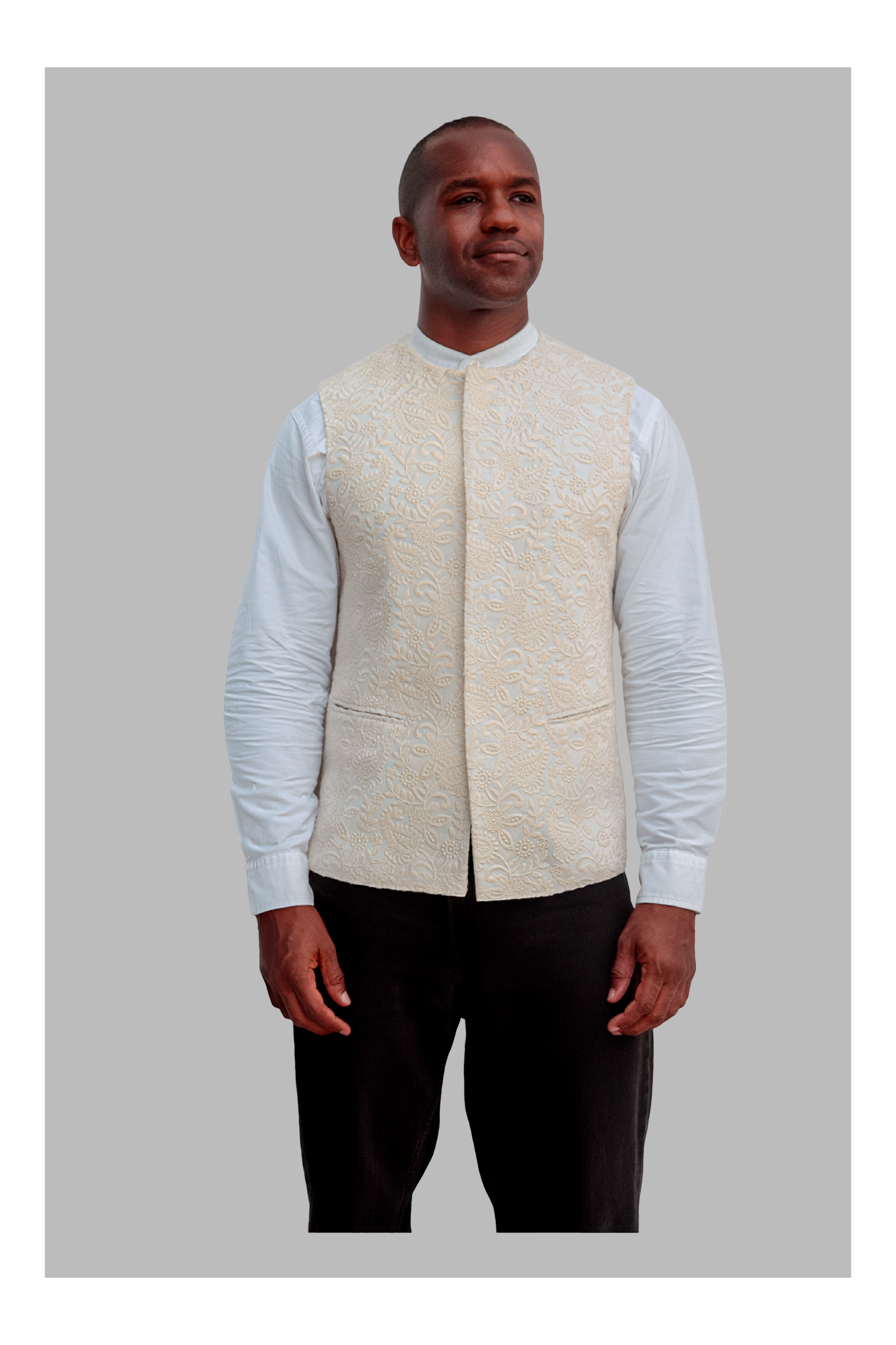 Man wearing a white patterned vest over a white shirt on a gray background