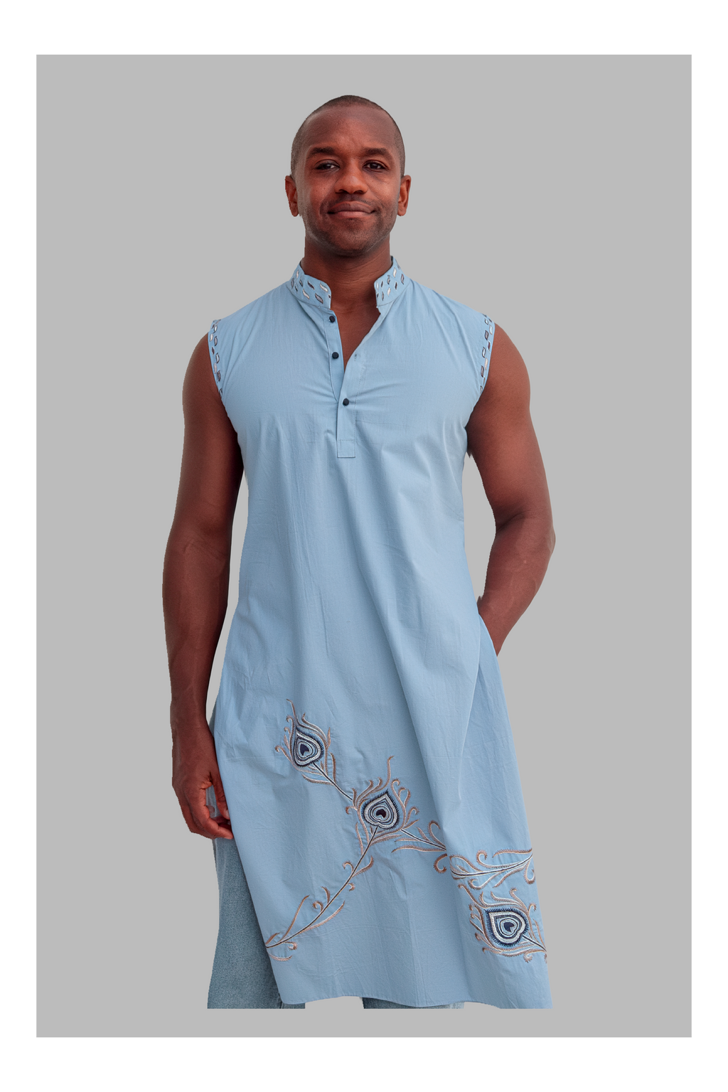 Man wearing a light blue sleeveless top with embroidery on a gray background