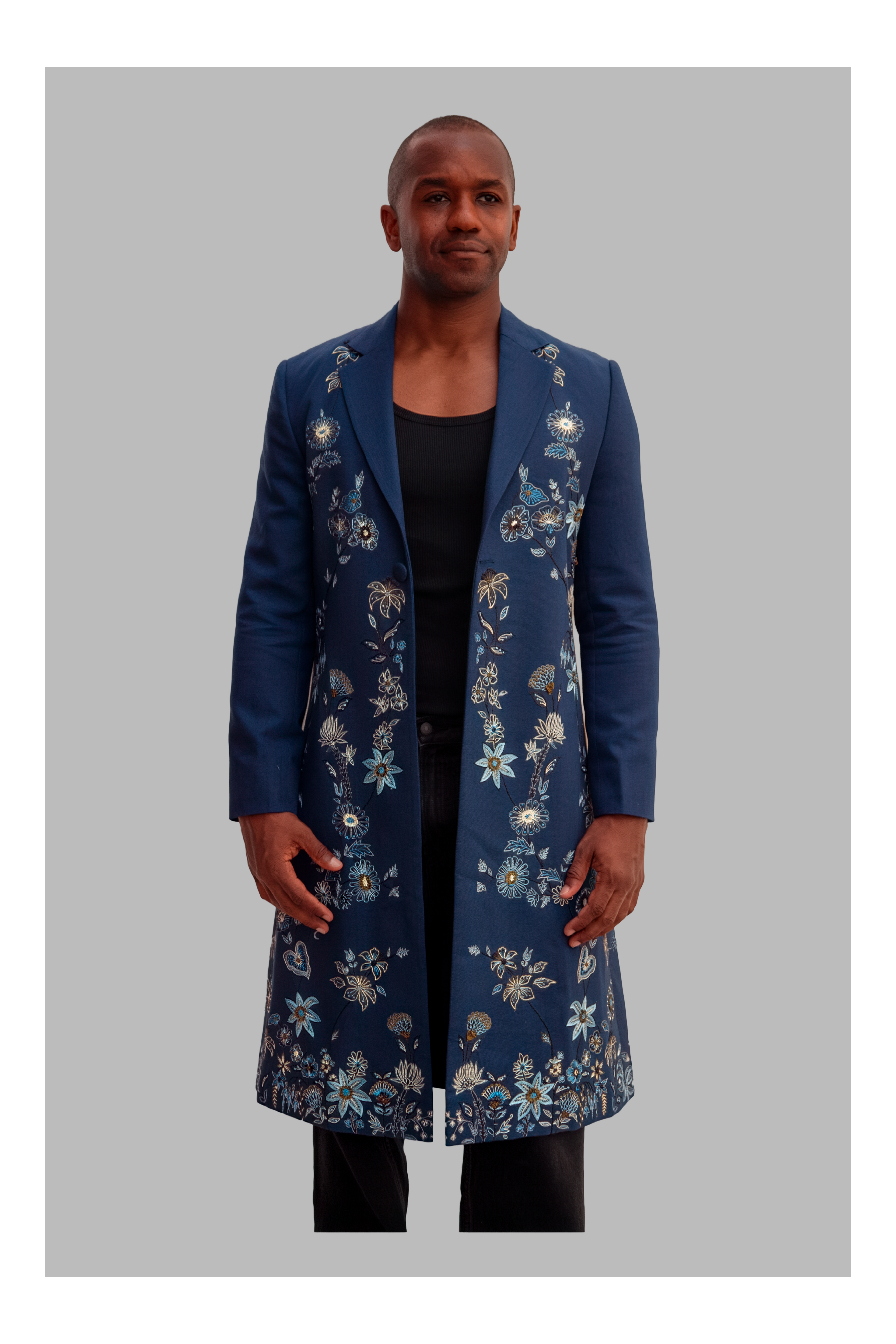 Man wearing a long blue floral coat on a gray background