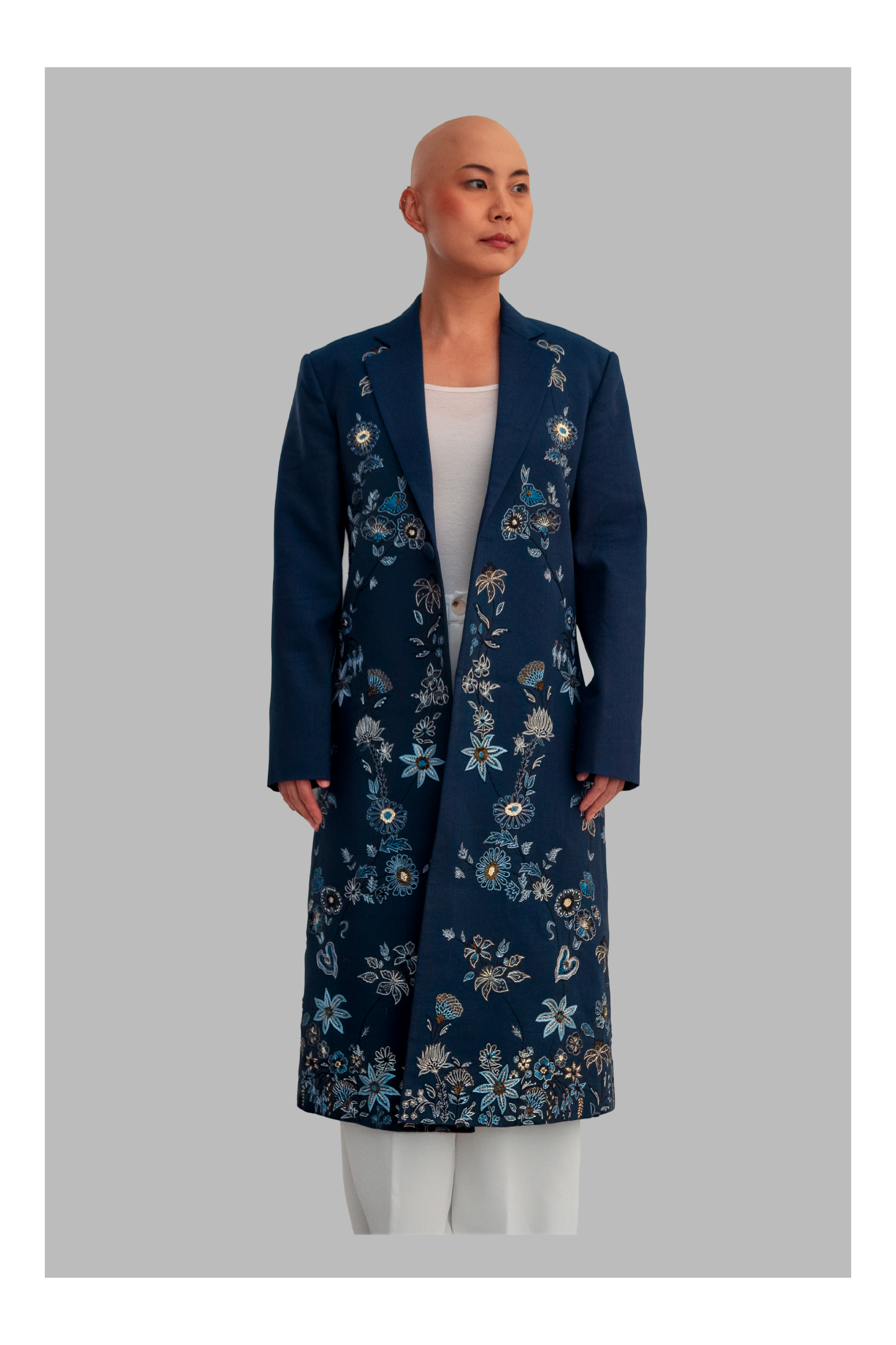 Woman wearing a long blue floral coat against a gray background