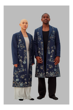 Two people wearing matching blue floral coats on a gray background
