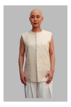 Female wearing a white vest with a textured pattern on a gray background