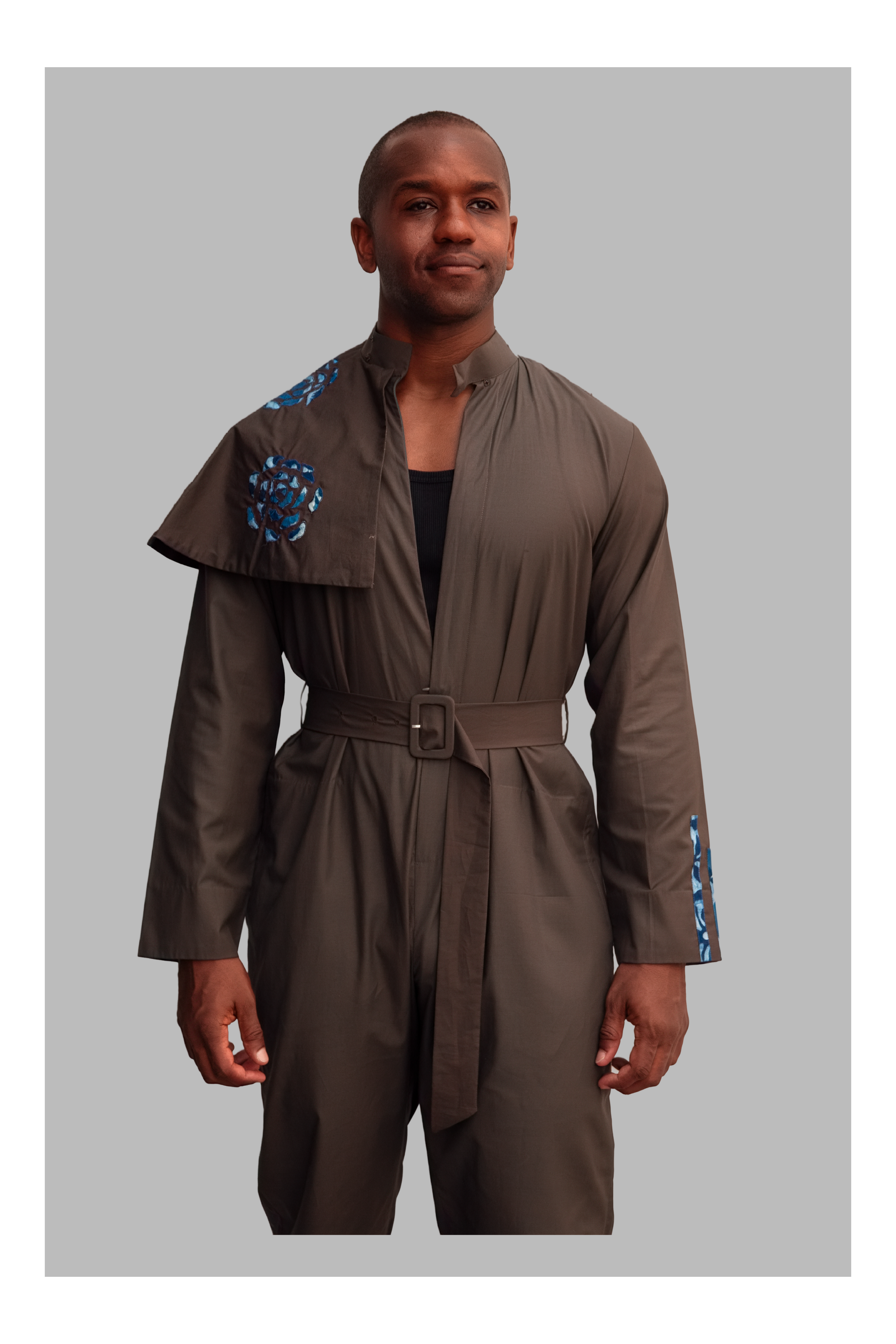 Man wearing a grey jumpsuit with blue accents on a gray background
