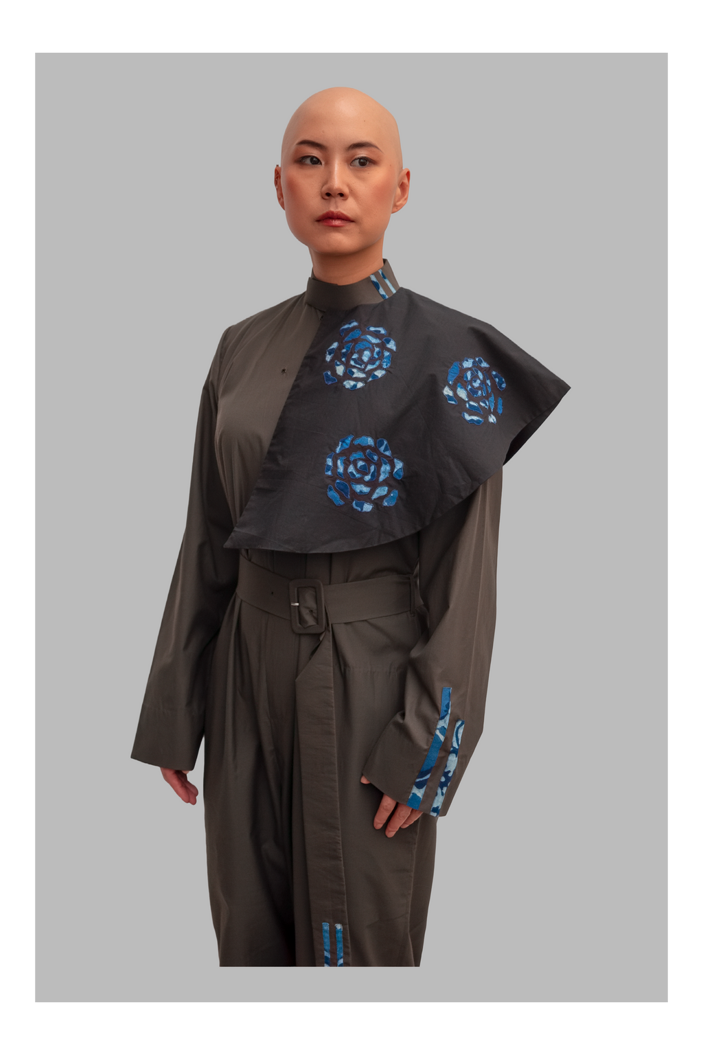 female wearing a grey jumpsuit with blue floral patterns on a gray background