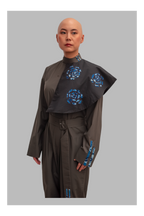 female wearing a grey jumpsuit with blue floral patterns on a gray background