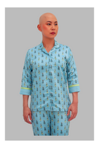 Person wearing a blue pajama set with a pattern on a gray background