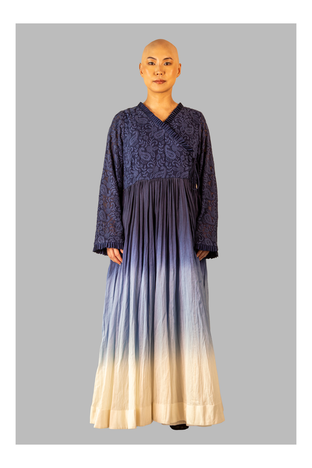 Female wearing a long, dark blue dress with a gradient effect on a gray background