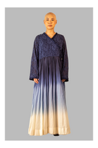 Female wearing a long, dark blue dress with a gradient effect on a gray background