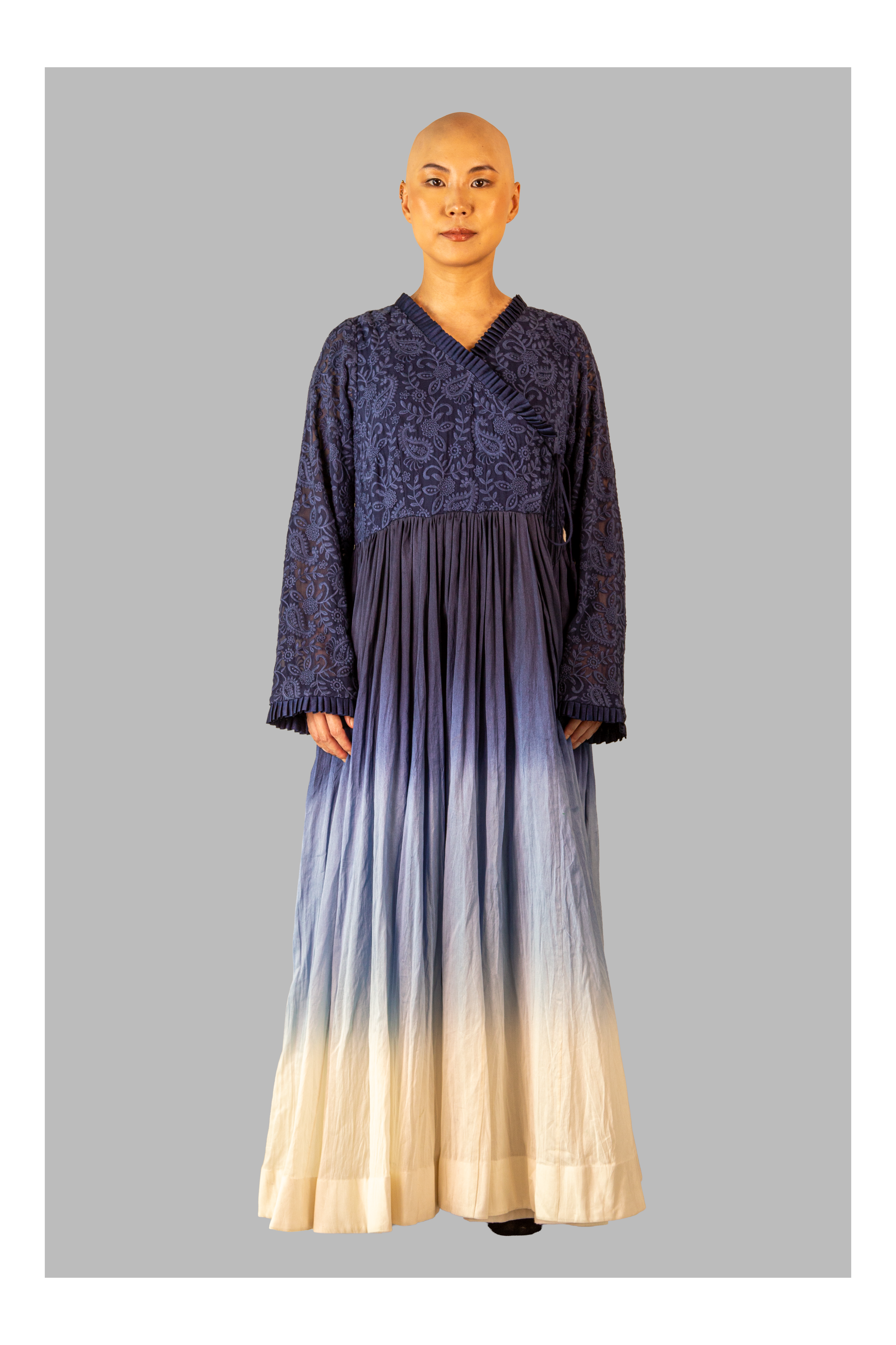 Female wearing a long, dark blue dress with a gradient effect on a gray background