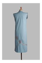 Light blue sleeveless top with peacock embroidery on a mannequin against a gray background