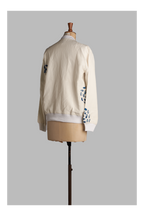 White jacket with floral patterns on sleeves displayed on a mannequin against a gray background