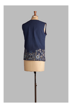 Navy blue sleeveless top with floral embroidery on a mannequin against a gray background