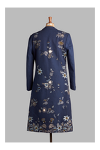 Navy blue long coat with floral embroidery on a mannequin against a gray background