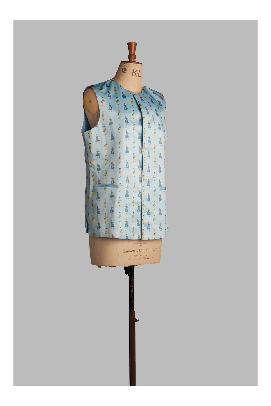 Light blue sleeveless jacket with printed pattern on a mannequin against a gray background
