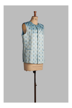 Light blue sleeveless jacket with printed pattern on a mannequin against a gray background