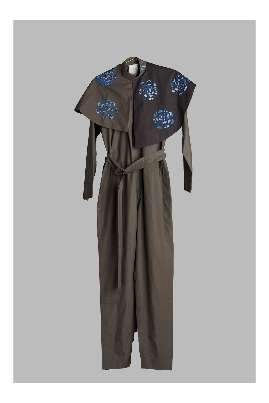 grey jumpsuit with belt and detachable collar accents on a grey background