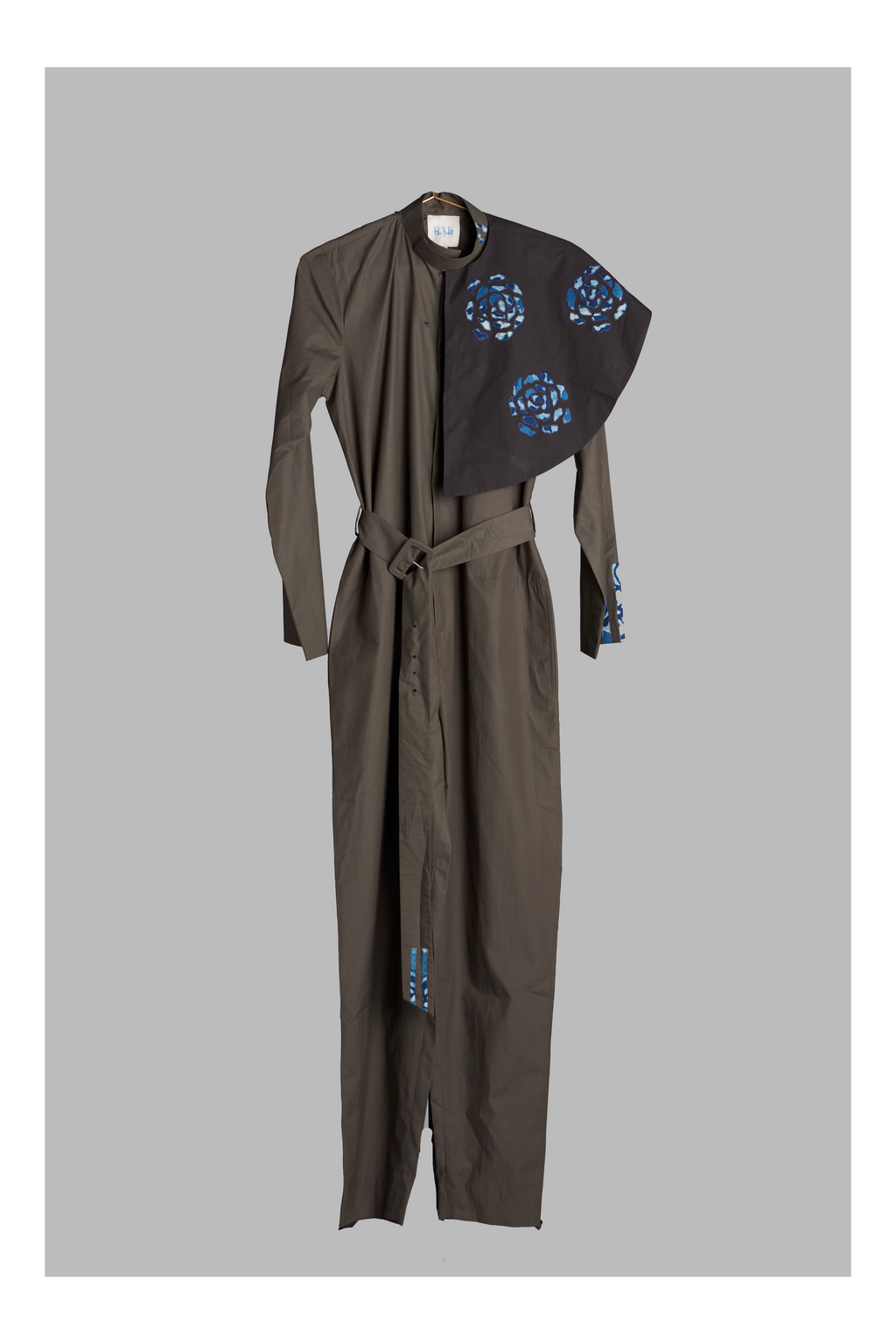 grey jumpsuit with belt and detachable collar accent on a grey background